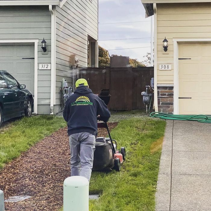 AL crew member in branded hoodie mowing a lawn