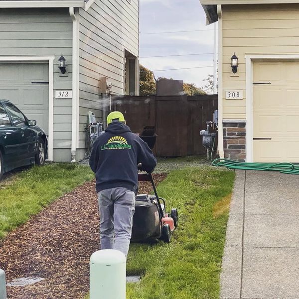 AL crew member in branded hoodie mowing a lawn